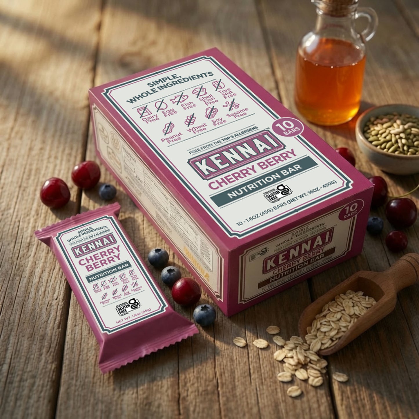 A boxed and individually wrapped Kennai Cherry Berry Nutrition Bar set on a rustic wooden table, surrounded by cherries and blueberries, oats in a wooden scoop, and a small glass bottle of honey.