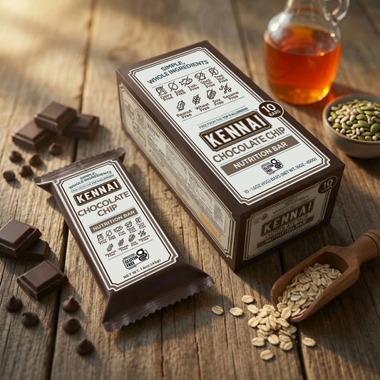 A boxed and individually wrapped Kenai Chocolate Chip Nutrition Bar set on a rustic wooden table, surrounded by chocolate pieces, oats in a wooden scoop, and a small glass bottle of honey.